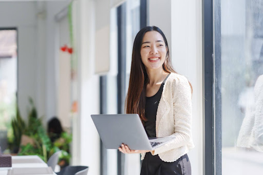 A smiling woman holding a laptop representing a startup owner with a new professional website