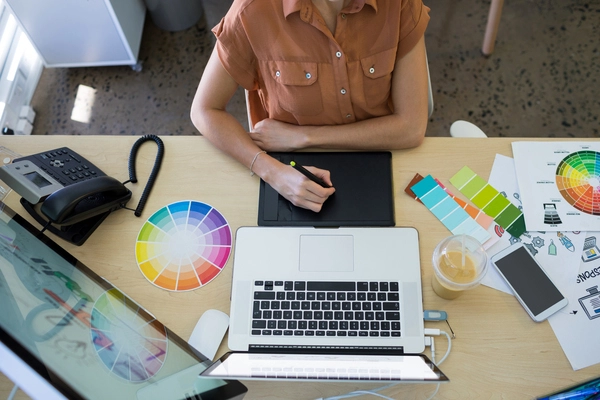 A professional web designer working on her desk, representing the value of investing in high-quality custom design to enhance brand authenticity.
