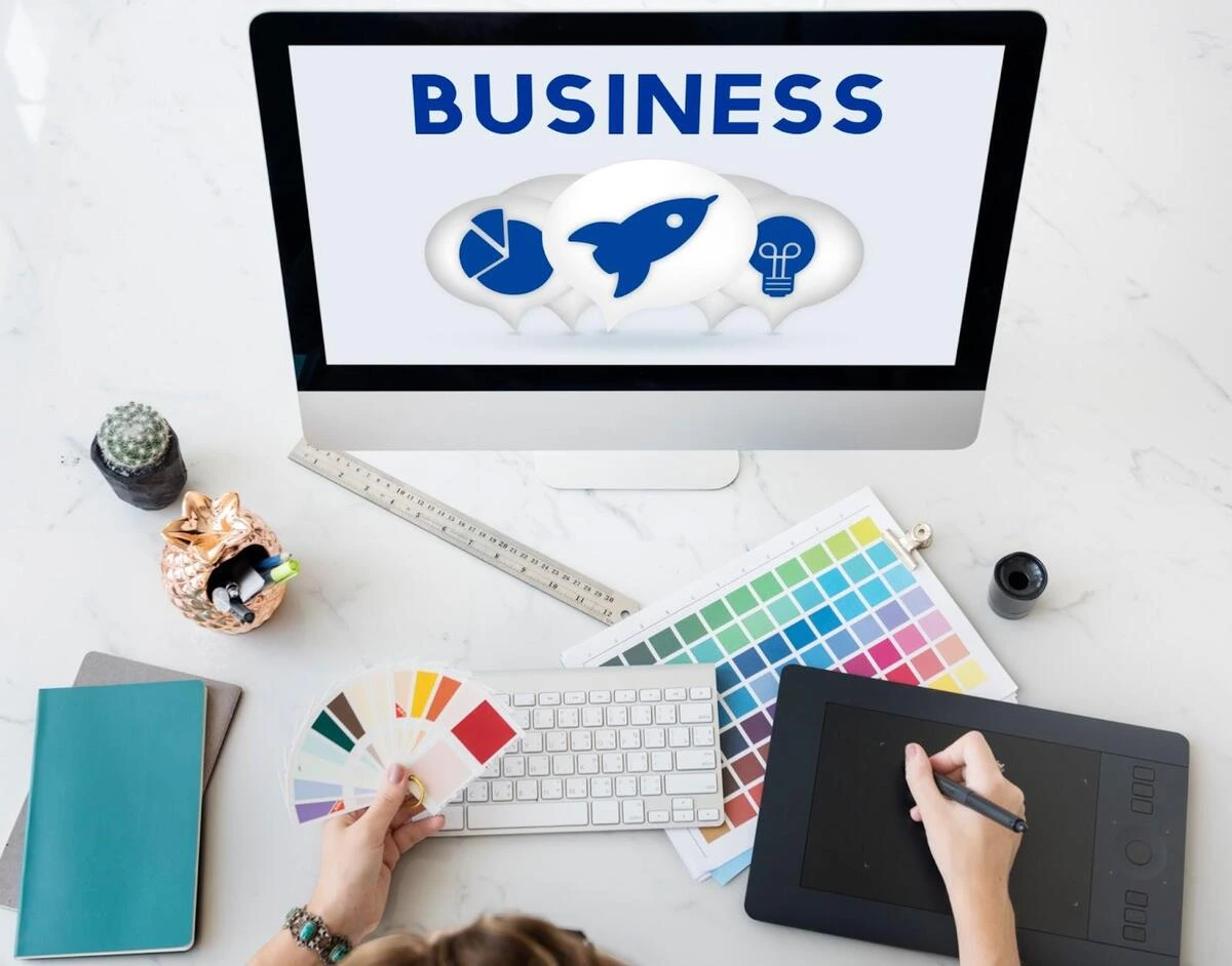 Overhead view of a web designer's desk with monitor, color swatches, keyboard, and design tools for small business website planning