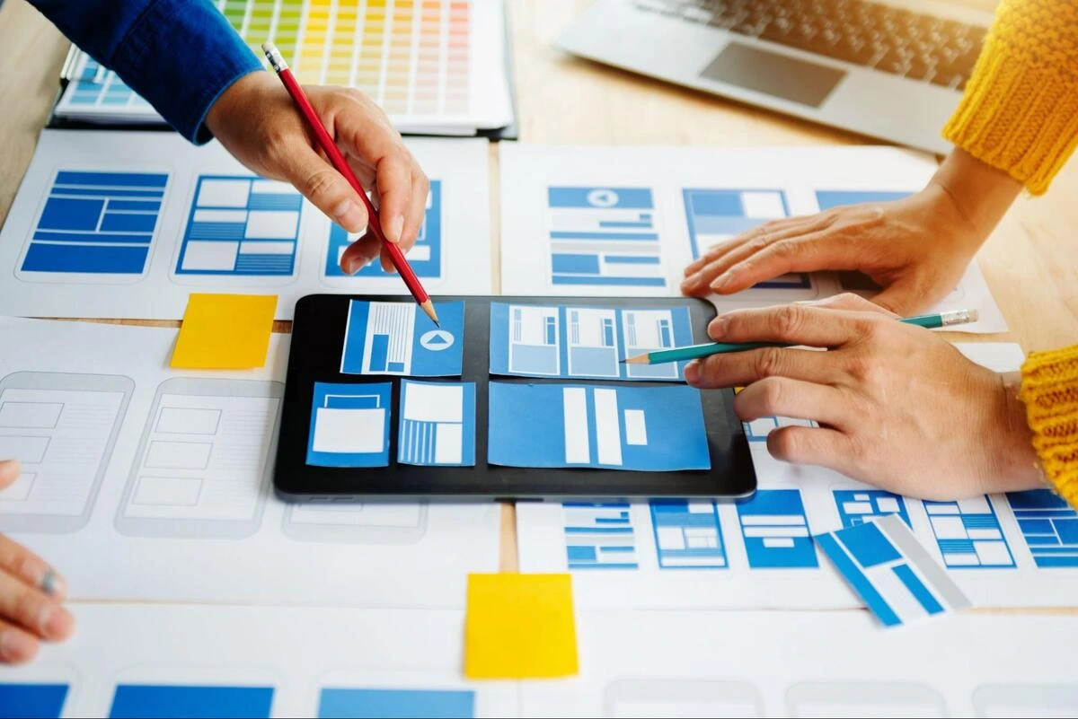 Communicating Clearly With a Web Design Agency Web design agency team reviewing printed wireframes and page layouts on a table