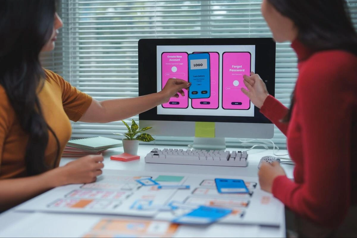Key Items to Prepare Before Hiring a Web Designer Two web designers reviewing user interface mockups on a desktop screen