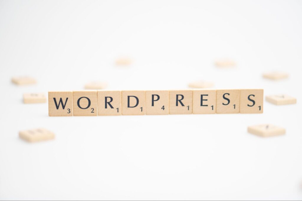 Scrabble tiles spelling out WORDPRESS arranged in a row on a white background 
