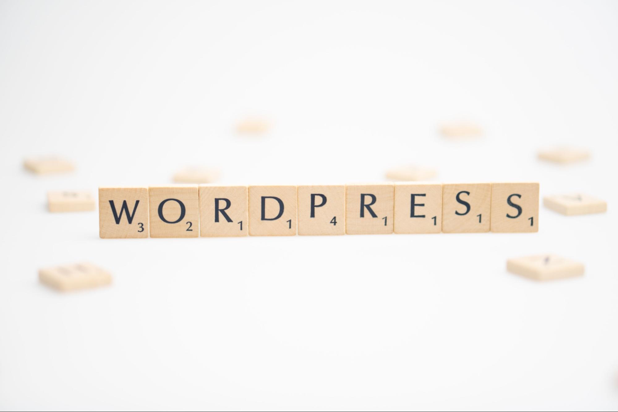 Scrabble tiles spelling out WORDPRESS arranged in a row on a white background